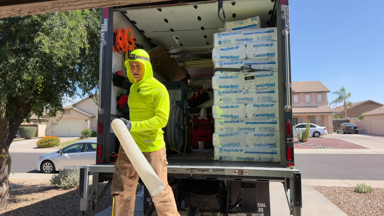 Bgreen team member preparing insulation hose beside CertainTeed fiberglass insulation in the truck